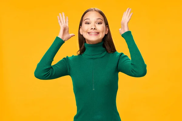 Χαρούμενη γυναίκα σε ένα πράσινο πουλόβερ χειρονομίες με τα χέρια της χαμόγελο κίτρινο φόντο — Φωτογραφία Αρχείου