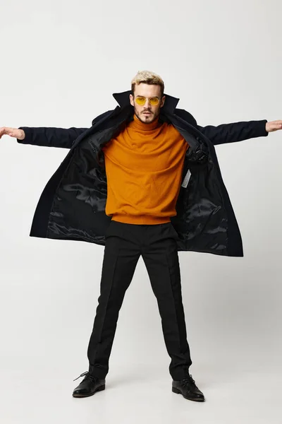 Energetic man in a coat spread his arms to the sides and pants orange sweater model — 图库照片