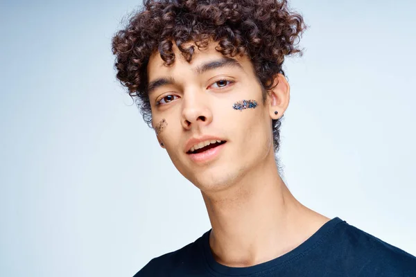 Guy with curly hair applies a black mask on his face cosmetology — Stock Photo, Image