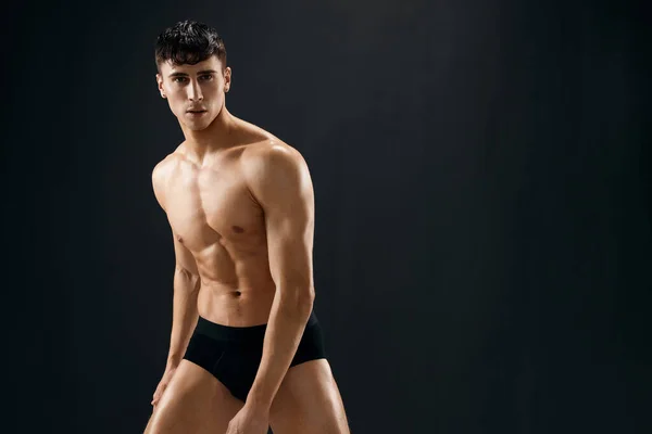 attractive athletic man in black shorts dark background