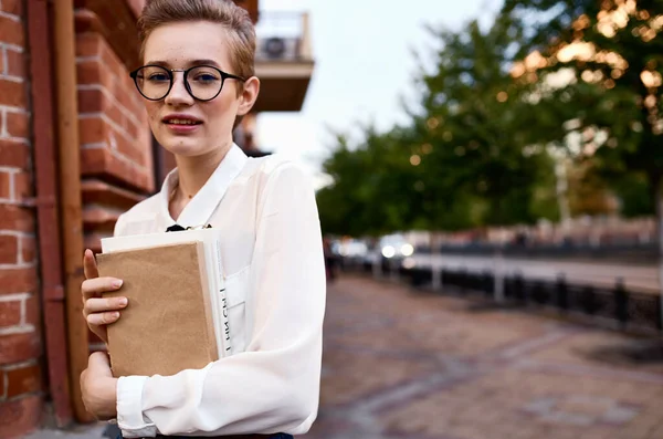 Studentka s knihou v blízkosti ústavu na ulici a brýlemi na tváři — Stock fotografie