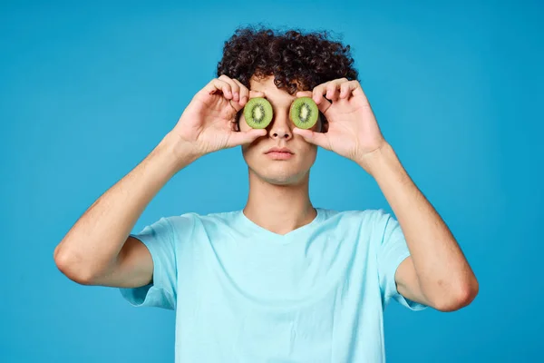 Hombre con el pelo rizado kiwi cerca de la cara fondo azul vista recortada — Foto de Stock