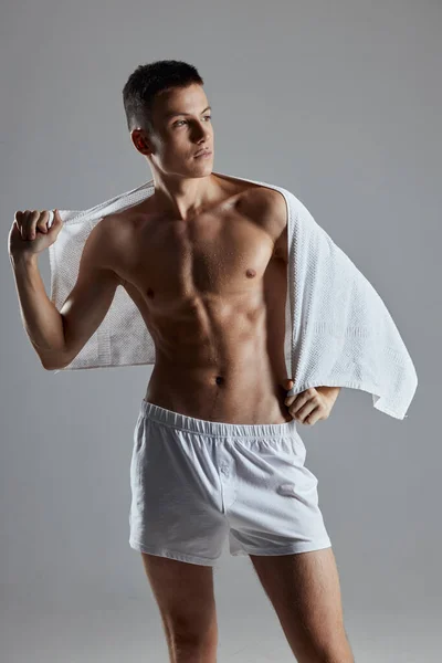 Homem nu torso em shorts brancos sobre os ombros posando isolado fundo — Fotografia de Stock