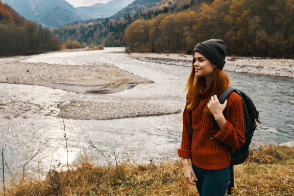 Viajero mujer con mochila en la orilla del río en la vista lateral de las montañas —  Fotos de Stock