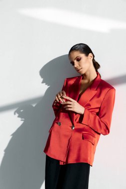 Güzel esmer, kırmızı ceketli ve siyah pantolonlu.