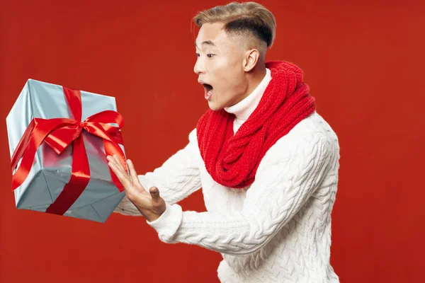 Azjata z pudełkiem prezentów na czerwonym tle i szalikiem na szyi świąteczne urodziny — Zdjęcie stockowe