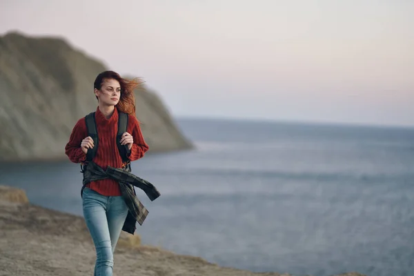 Woman hiker with backpack walking along the beach near the sea in the mountains — Stock Photo, Image