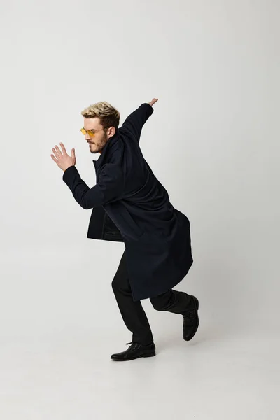 Férfi visel szemüveg divat frizura fekete kabát mozgás tánc elszigetelt háttér — Stock Fotó