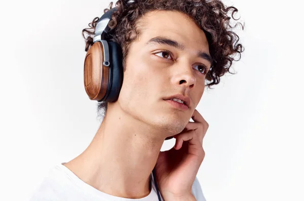 Tipo con el pelo rizado en los auriculares escucha música sobre un fondo claro — Foto de Stock