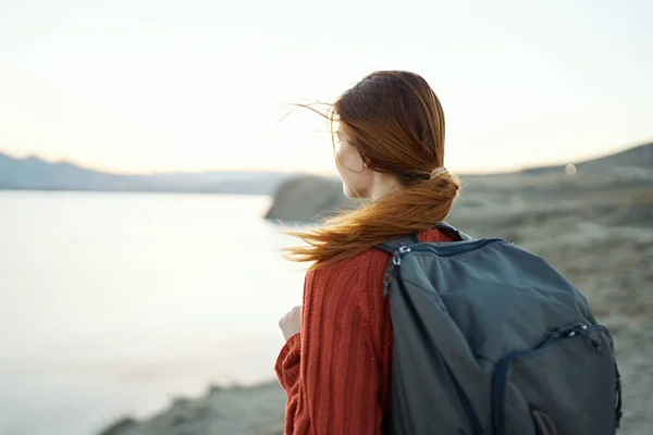 Donna viaggia in montagna nella natura vicino al mare con uno zaino sulla schiena — Foto Stock