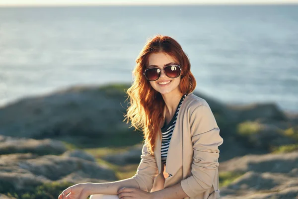 Kobieta w okularach przeciwsłonecznych i w różowym swetrze spodnie Rock of the sea ocean — Zdjęcie stockowe