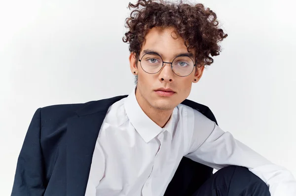 Retrato de um cara de cabelos encaracolados em uma camisa em uma jaqueta e óculos em um fundo leve close-up — Fotografia de Stock