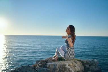 Gezgin, deniz kenarında, dağlarda ve günbatımında sahilde oturur.