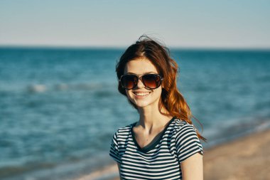 Güneş gözlüklü güzel bir kadın, dağlarda deniz kenarında.