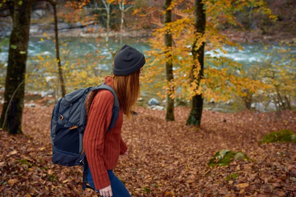 Vrouw met rugzak reizen toerisme bos landschap park rivier gevallen bladeren zijaanzicht — Stockfoto