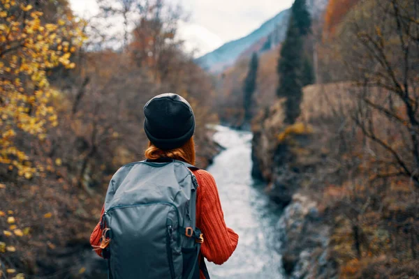 Mulher feliz caminhante com mochila em suas costas perto do rio da montanha na natureza vista traseira — Fotografia de Stock