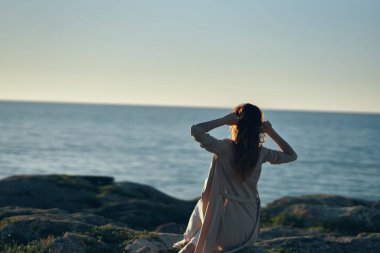 Kadın, akşamları dağlardaki manzaraya hayran ve elleriyle el hareketleriyle mekanı taklit ediyor.