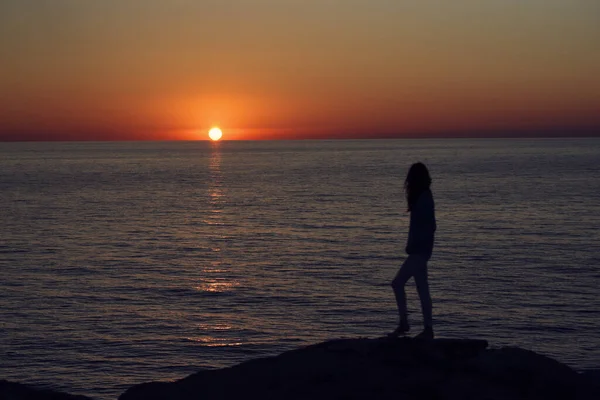 Sonnenuntergang in den Bergen am Meer und eine weibliche Silhouette am Strand — Stockfoto
