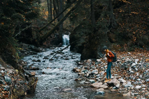 Vrouw in een trui hoed in de buurt van de rivier en bomen op de achtergrond — Stockfoto