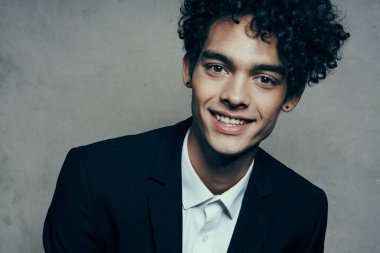 Takım elbiseli, kıvırcık saçlı, kendine güvenen bir iş adamı.