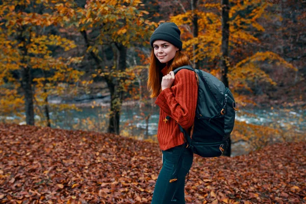 Podzim park spadl listí vysoké stromy řeka v pozadí a žena cestovní ruch — Stock fotografie