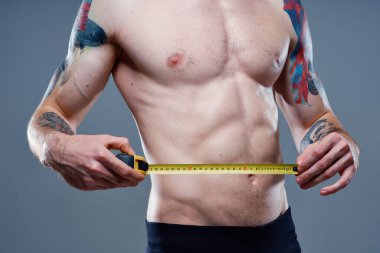 Ateşli kol kasları ve santimetre bant vücut geliştirici formda seksi bir sporcu.