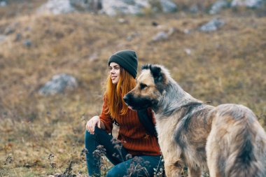 Doğa yürüyüşçüsü, doğa manzarası dağlarında köpeğe sarılır.