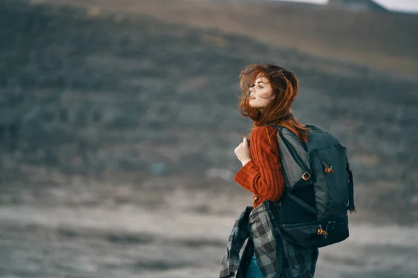 Rothaariger Reisender mit Rucksack blickt zurück auf die Natur in den Bergen — Stockfoto