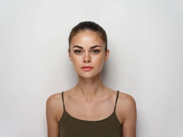 Bonita jovem mulher em uma t-shirt em um fundo leve penteado maquiagem modelo — Fotografia de Stock