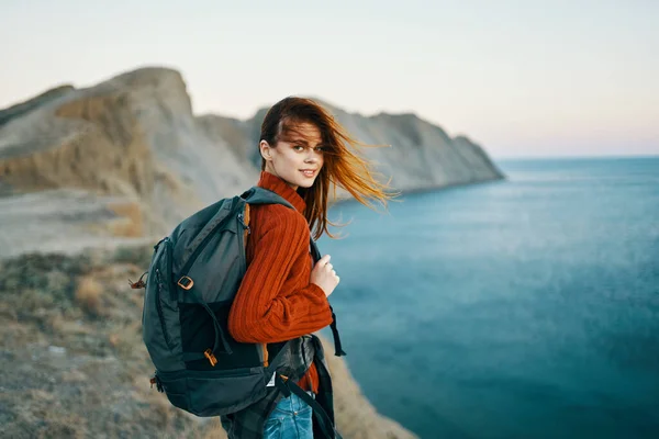 Жінка в светрі з рюкзаком ходить в природі в горах біля моря — стокове фото
