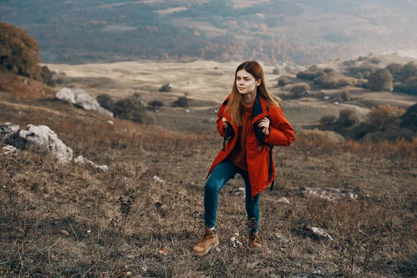 Žena turista v bundě boty s batohem cestování v horách krajina — Stock fotografie