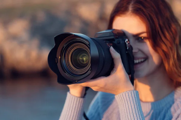 Όμορφη κοκκινομάλλα γυναίκα με μια φωτογραφική μηχανή στη φύση στα βουνά κοντά στο ποτάμι — Φωτογραφία Αρχείου