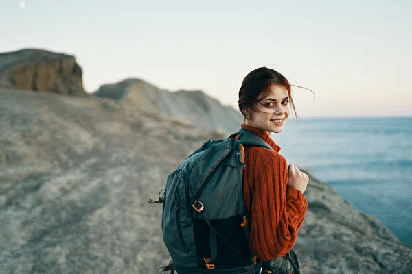 Beautiful woman hiker with a backpack on her back in the mountains near the sea landscape model — Stock Photo, Image