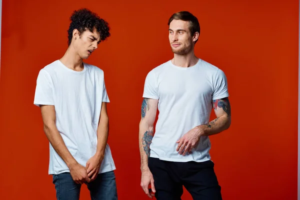 Due uomo in bianco t-shirt comunicazione amicizia rosso sfondo — Foto Stock