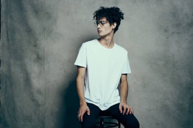 Kıvırcık saçlı, gözlüklü beyaz tişörtlü stüdyo modası