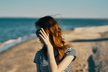 İş yerinde, plajda güneş gözlüklü kadın tişörtü giyip hava tatili yapacaksın.