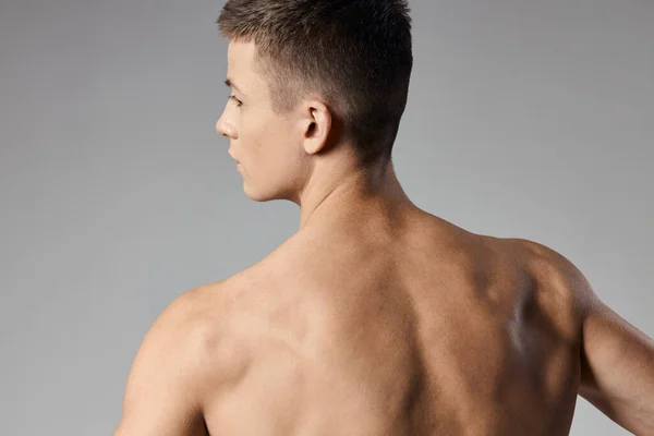運動選手が腕の筋肉を裸に戻るグレーの背景モデルクロップドバックビュー — ストック写真