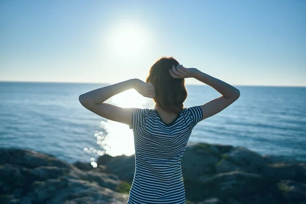 Happy traveler woman gesturing with her hands near the sea in nature and sunset in the distance — Stock Photo, Image