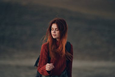 Sırt çantalı güzel bir kadın doğada çayırda yürüyor.