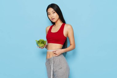 Atletik kadın zayıf vücut sağlıklı, mavi arka plan yiyor.