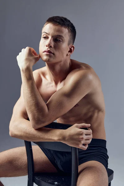 Sporty man sitting on a chair leaning on the back isolated background posing — Stock Photo, Image