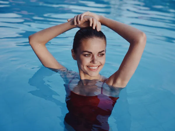 Женщина в красном купальнике в бассейне роскошные руки над головой — стоковое фото