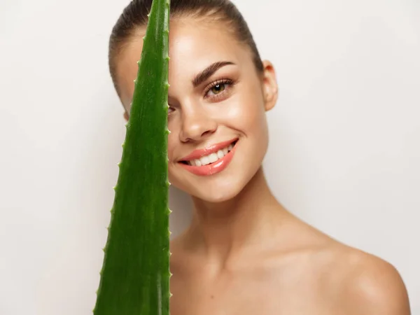 Mujer feliz sonriendo y sosteniendo hoja de aloe verde en la mano divertido —  Fotos de Stock