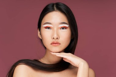 Asyalı kadın. Parlak makyaj. Çıplak omuzlar.