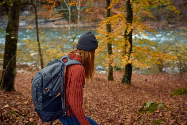 Vrouw met rugzak reizen toerisme bos landschap park rivier gevallen bladeren zijaanzicht — Stockfoto