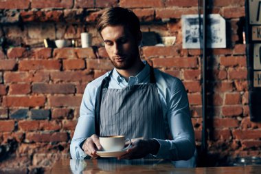 Erkek garson önlüğü kahve fincanı tuğla duvar