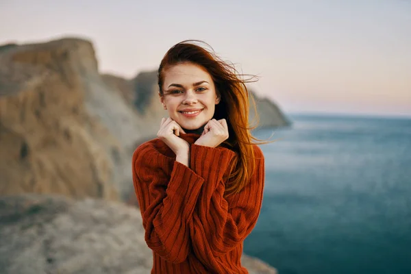 Femme heureuse dans un pull rouge dans les montagnes dans la nature et la mer en arrière-plan — Photo