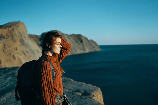 Mulher bonita em uma camisola com uma mochila perto do mar na natureza — Fotografia de Stock