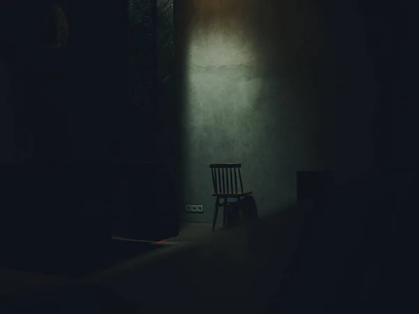 Une chaise se tient au milieu d'une silhouette de pièce sombre d'un intérieur de lumière tombante — Photo