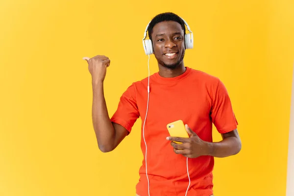 Homem de aparência africana em fones de ouvido música fundo amarelo — Fotografia de Stock